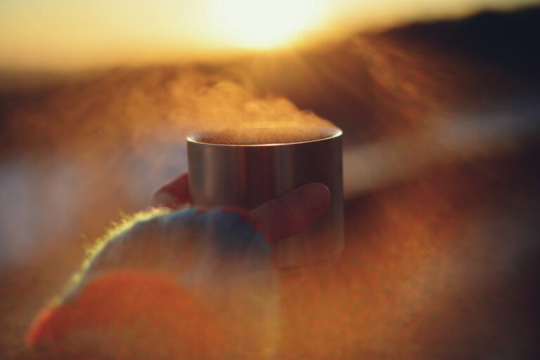Steam rising from a cup held in cupped hands in soft golden morning light, a quiet ritual moment